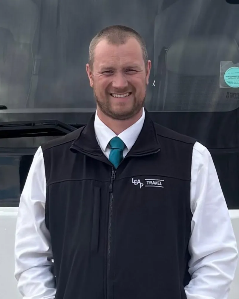 Jake, owner of Leap Travel, in uniform in front of a Leap Travel coach